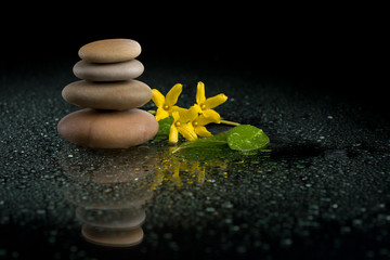 balancing zen stones on black with yellow flower