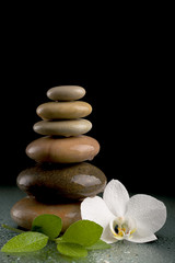 Fototapeta na wymiar balancing zen stones on black with white flower