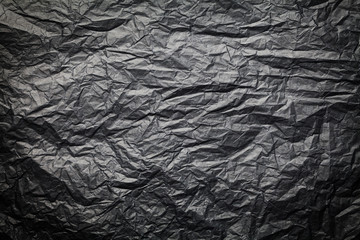 The dark texture of crumpled paper, black background