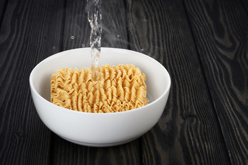 Cooking instant noodles, pouring boiling water.