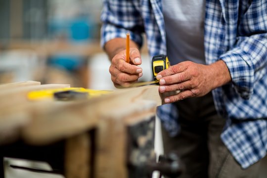Carpenter measuring a length of wooden plank