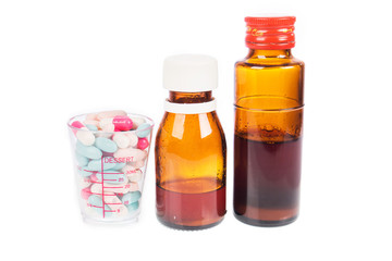 Syrup Medication Bottles and Medicine in Spoons on white backgro