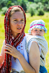 Obraz premium Mother carrying her child in a baby sling