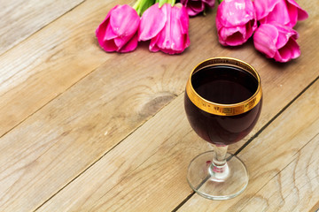 glass with red wine and tulips