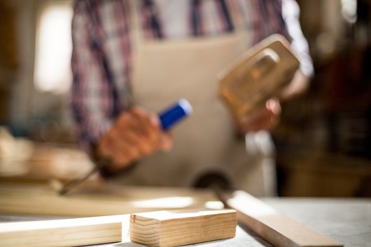 Close-up of carpenter working on wooden plank on workbench