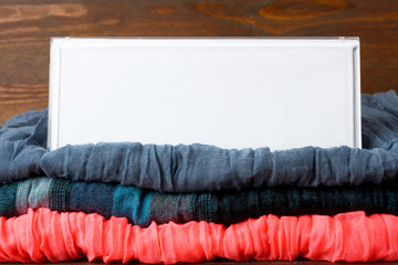 white tag on a stack of colorful folded clothes closeup on wooden background