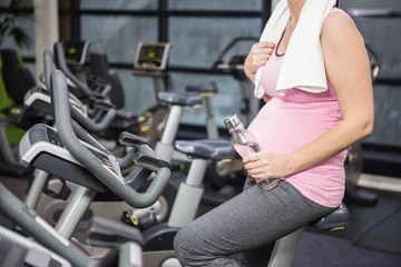 Fototapeta na wymiar Mid section of pregnant woman on exercise bike