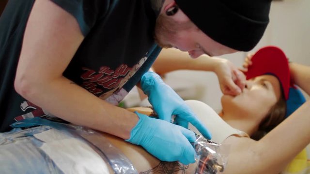 Tattoo artist make tattoo at studio girl in pain