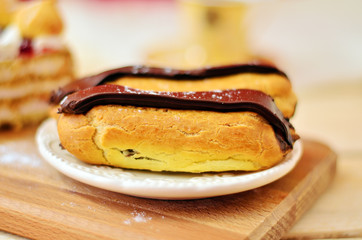Eclairs with chocolate close-up on a wooden table