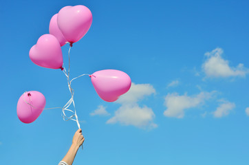 Hand holding balloons flying in the sky