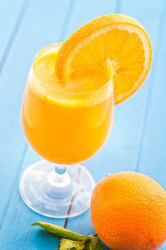 fresh orange juice with orange slice in glass on blue wooden background, orange, mango, drink, product photography for healthy lifestylea