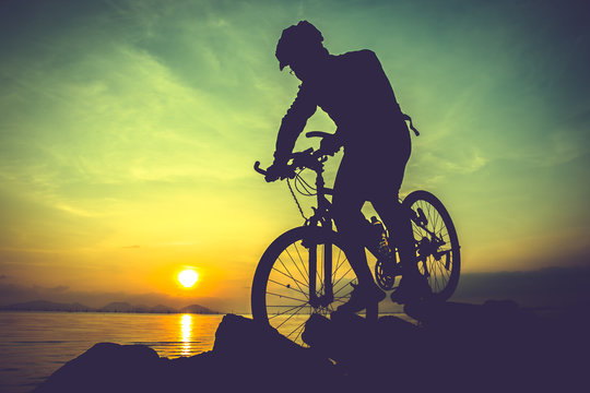 Healthy lifestyle. Silhouette of bicyclist riding the bike at seaside