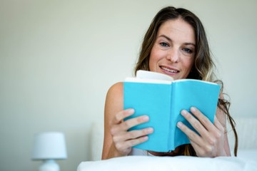 smiling woman in bed reading a book