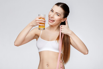 sporty woman over gray background holding glass of orange juice