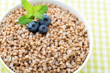 Buckwheat porridge in a bowl with mint leaves and blueberries.