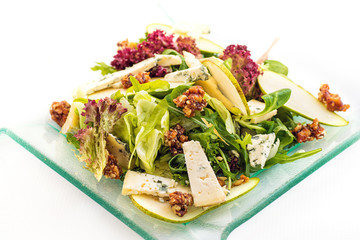 fresh lettuce salad with blue cheese, pear and caramelized walnuts on glass plate isolated on white background, product photography for restaurant and healthy lifestyle