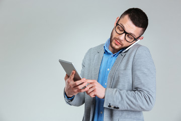 Businessman talking on the phone and using tablet computer