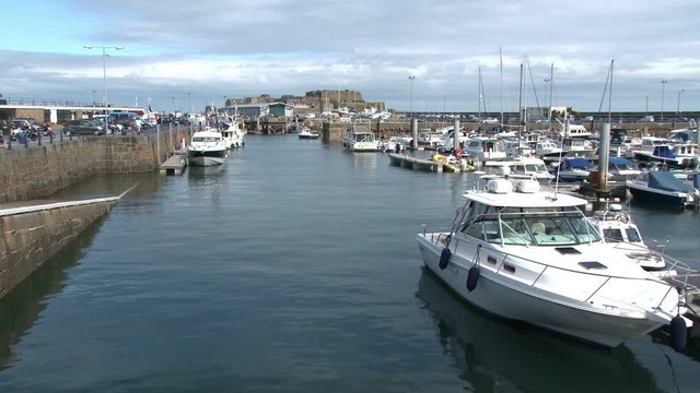 View over the harbour and marina of St Peter Port, Guernsey on a sunny summer day. Castle Cornet is in the background