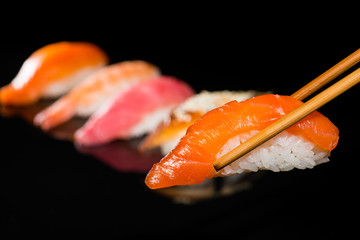close-up nigiri with salmon on chop sticks