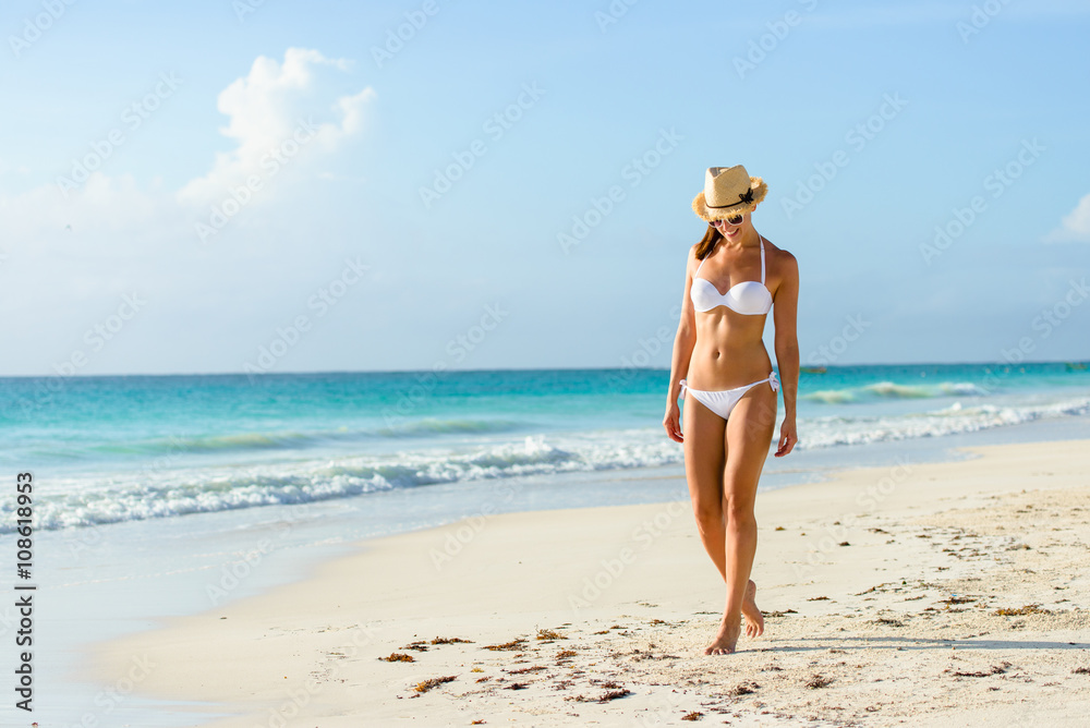 Wall mural relaxed woman in bikini enjoying tropical beach and caribbean summer vacation. fit tanned brunette e