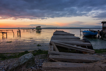 Fototapeta na wymiar After sunset on old wooden pier and boat at a lake coast near Varna, Bulgaria