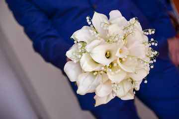 Groom holding white calla lily flower