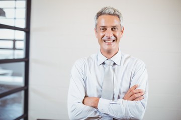 Portrait of smiling business professional with arms crossed standing in office