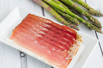 Fresh asparagus with delicious ham on plate. Preparation for cooking asparagus rolled in ham.