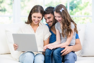 Family sitting on sofa and looking at laptop 