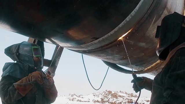 Industrial workers welding steel duct pipe by using metal torch