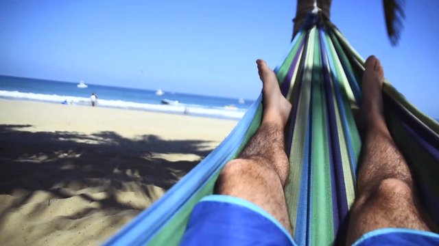 Feet swinging in a hammock, POV. Relaxing on the beach