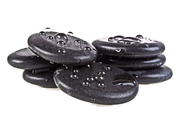 Black massage stones stacked, isolated on white background