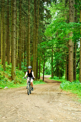 Obraz premium Young woman cycling in forest. Riding a bike. Young woman doing sports in forest, South Moravia, Czech Republic.