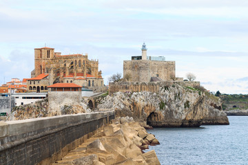 Fototapeta na wymiar Breakwater of Castro Urdiales, with the church of Santa Maria de la Asuncion and Castle Lighthouse in the background