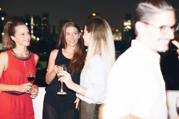 Happy people on rooftop party. Cityscape view at night.