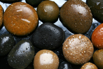 Wet colored stones background, dark pebbles with water drops 