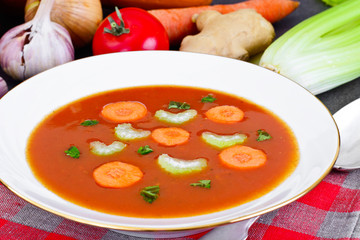 Carrot Tomato Soup in Plate. Behind lie on the soup ingredients,