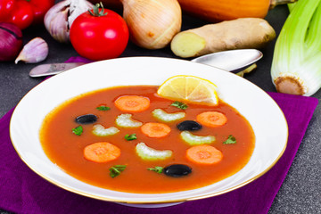 Carrot Tomato Soup in Plate. Behind lie on the soup ingredients,