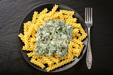 Italian pasta with spinach sauce  on black plate.