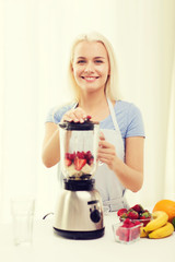 Obraz na płótnie Canvas smiling woman with blender preparing shake at home