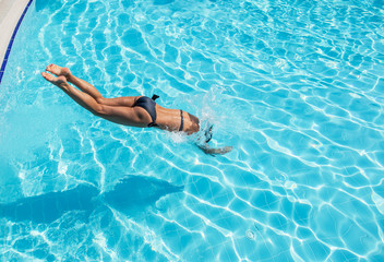 Woman jumping into the swimming pool.