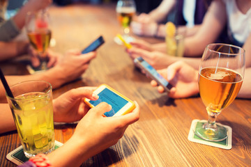 close up of hands with smartphones at restaurant