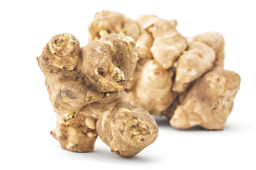 Pile of fresh raw Jerusalem artichoke, one in front, isolated on white background