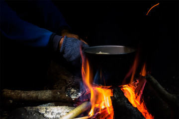 Cooking by using a pot and bonfire at night camping.