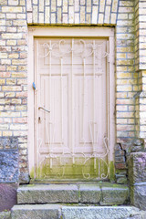 Old wooden door with grating in a brick wall
