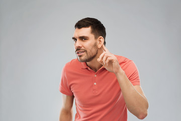 man having hearing problem listening to something