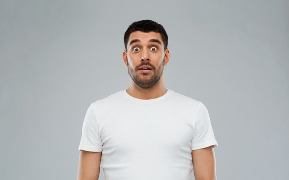 scared man in white t-shirt over gray background
