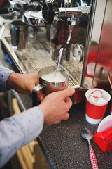 Coffee shop worker steams milk for a hot latte