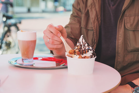 Hands Of Man Eating Frozen Yogurt At Cafe Table