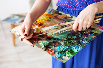 palette with paintbrush and palette-knife in artist’s hands.